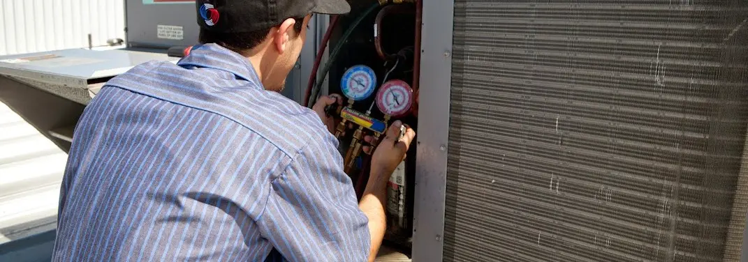 HVAC technician servicing a condenser unit in Rifle